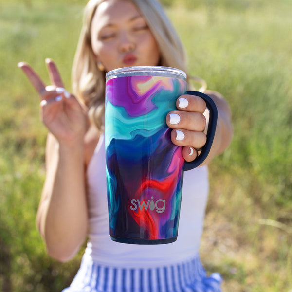 Swig Life Insulated Aura 22oz Travel Mug being held by a women outside on a grassy field