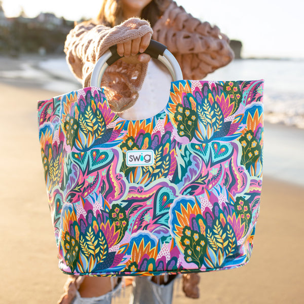 Swig Life Bazaar Loopi Tote Bag being held by a women on a sandy beach