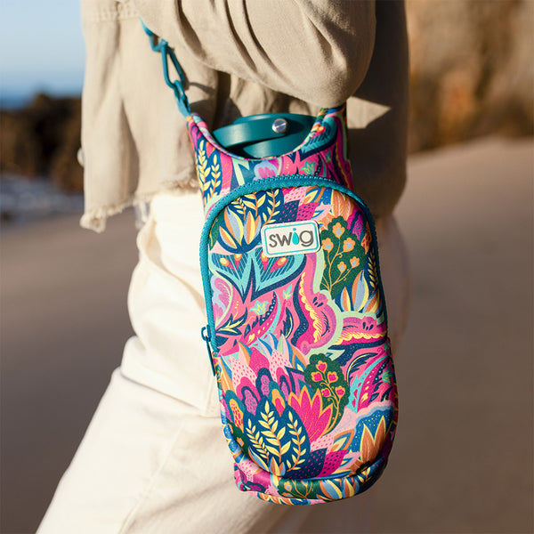 Swig Life Bazaar Water Bottle Sling worn over the shoulder of a woman walking on the beach