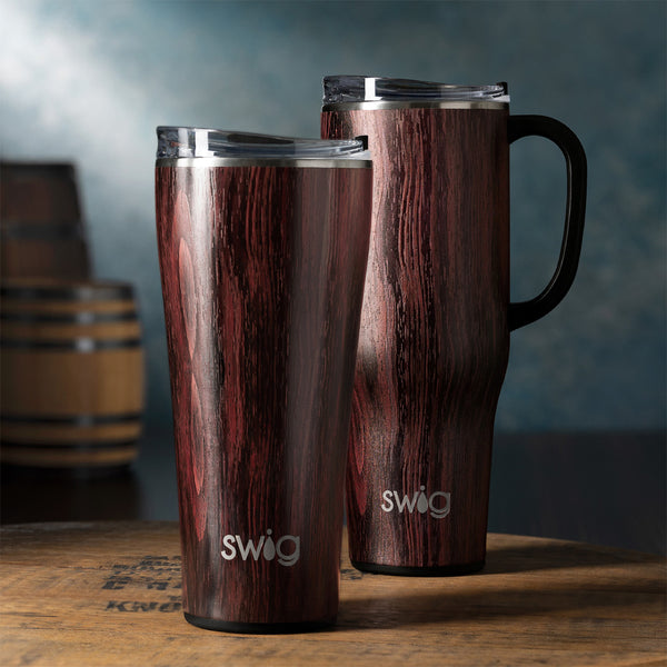 Swig Life Bourbon Barrel Mega Set including a 32oz Tumbler and a 40oz Mega Mug on a wooden desk over a dark classic background