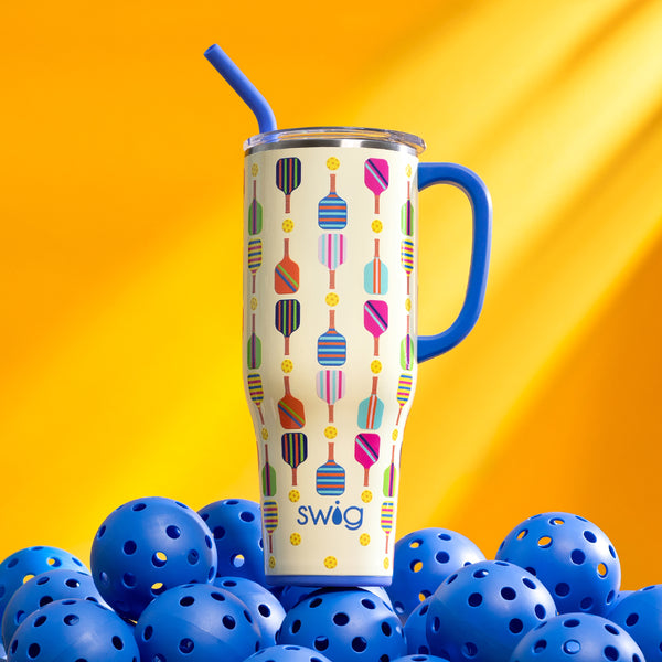 Swig Life 40oz Pickleball Insulated Mega Mug on a pile of blue pickleballs over a yellow background