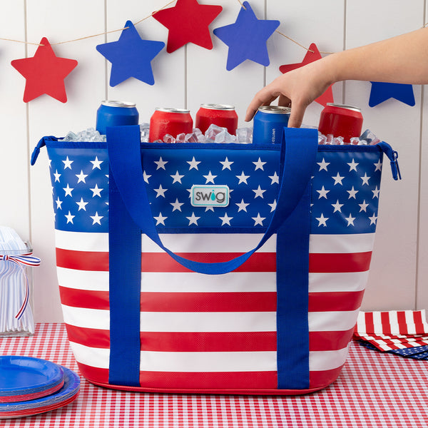 Swig Life All American Insulated Zippi Cooler filled with ice and cans on a red and white gingham tablecloth