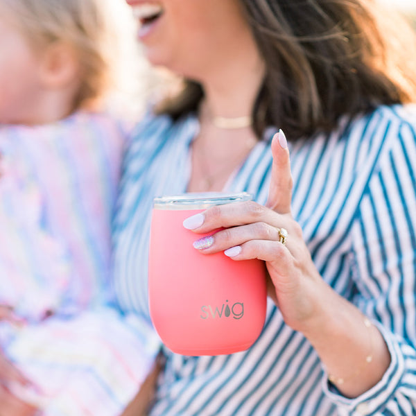 Woman in a blue striped shirt holding a Swig Life 14oz Coral Insulated Stemless Wine Cup